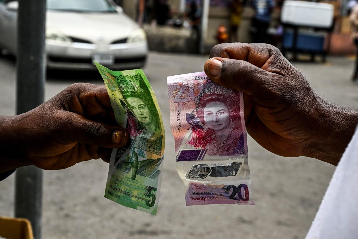 An image of Britain's late Queen Elizabeth II is seen on Eastern Caribbean dollar bills as a woman purchases fruit in a market in Saint John's, Antigua and Barbuda, on September 16, 2022. - The queen is to be buried in a state funeral on September 19, 2022. (Photo by CHANDAN KHANNA / AFP) (Photo by CHANDAN KHANNA/AFP via Getty Images)