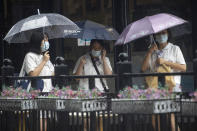 Residents wearing masks to prevent the spread of the coronavirus take cover from a rainstorm in Beijing on Wednesday, Aug. 5, 2020. A downpour in the Chinese capital provided relief from the summer heat. (AP Photo/Ng Han Guan)