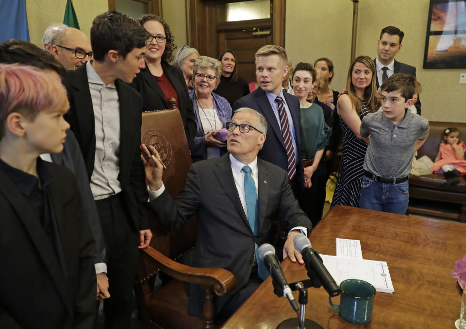 Washington Gov. Jay Inslee, center, turns to talk with Katrina Spade, upper left, the founder and CEO of Recompose, a company that hopes to use composting as an alternative to burying or cremating human remains, Tuesday, May 21, 2019, at the Capitol in Olympia, Wash., before signing a bill into law that allows licensed facilities to offer "natural organic reduction," which turns a body, mixed with substances such as wood chips and straw, into soil in a span of several weeks. The law makes Washington the first state in the U.S. to approve composting as an alternative to burying or cremating human remains. (AP Photo/Ted S. Warren)