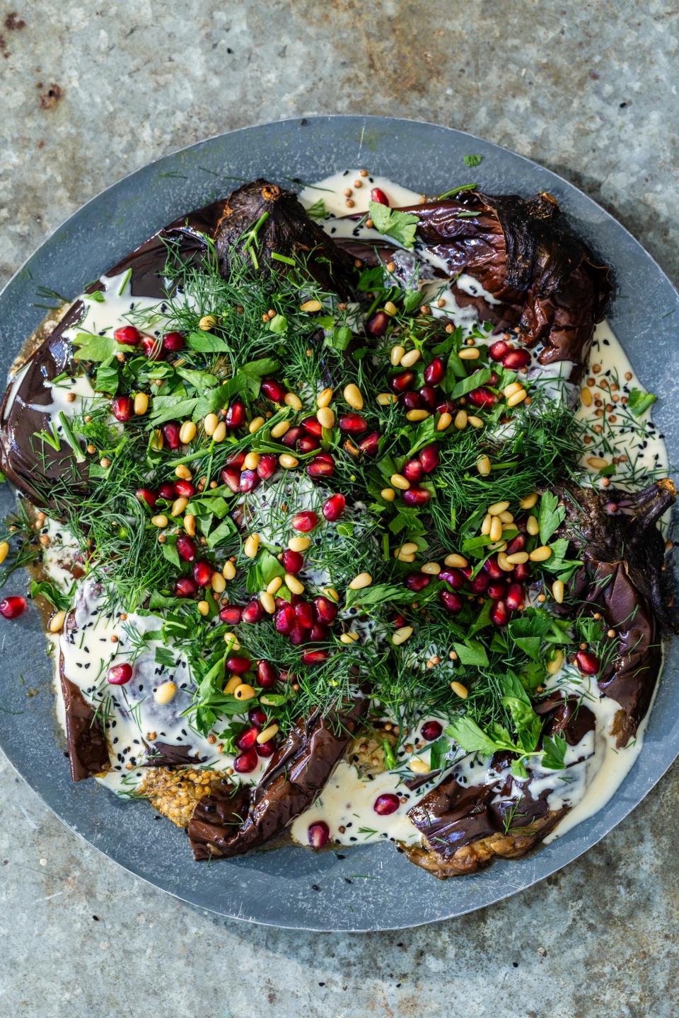 Roasted eggplants in tahini served with dill, pomegranate, and pine nuts