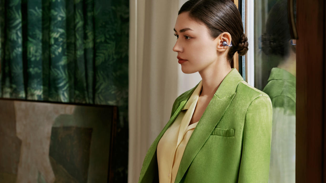  Huawei FreeClip earbuds worn by woman in green jacket. 