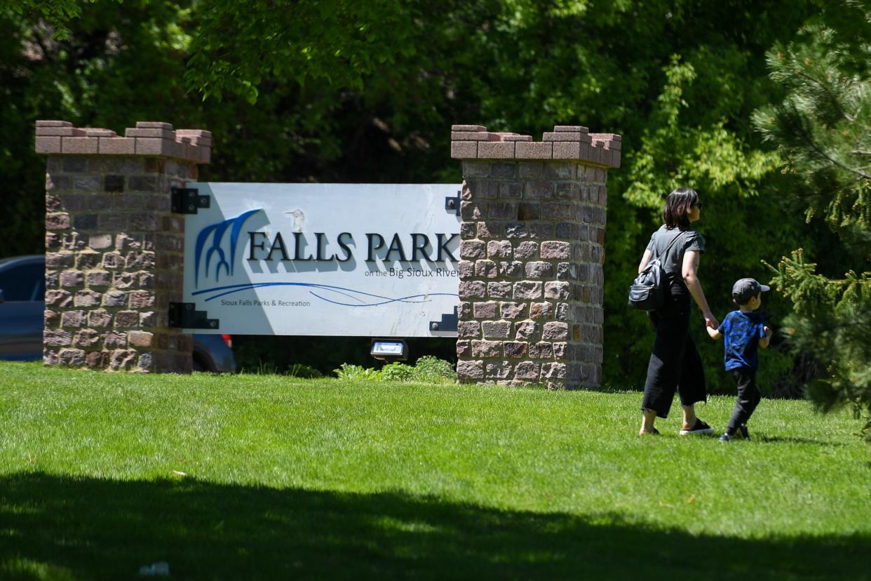 A parent and child walk by the front park sign on Saturday, May 11, 2024, at Falls Park in Sioux Falls.