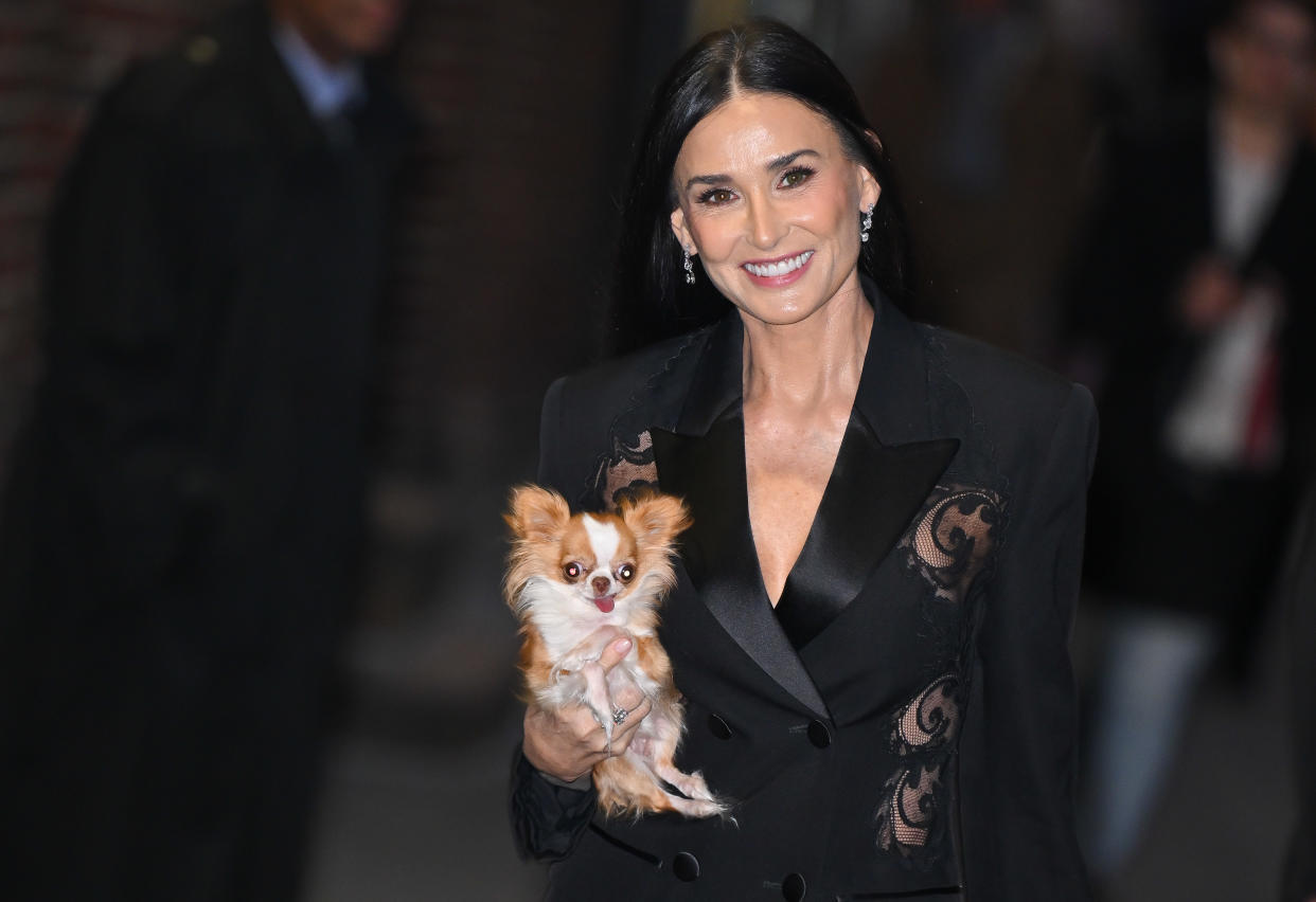 Demi Moore holds her dog Pilaf in her right arm.