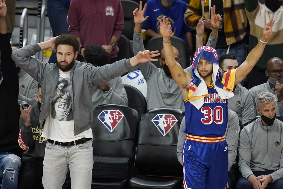 Injured Golden State Warriors guard Klay Thompson, left, and guard Stephen Curry (30) celebrate during the second half of the team's NBA basketball game against the Phoenix Suns in San Francisco, Friday, Dec. 3, 2021. (AP Photo/Jeff Chiu)