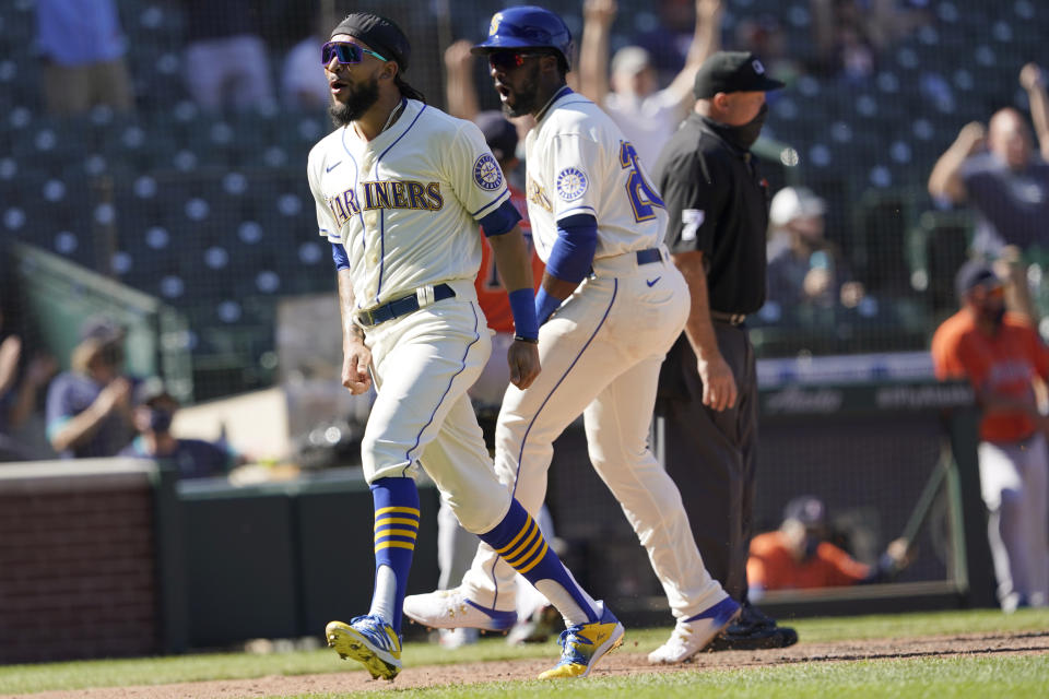 Seattle Mariners' J.P. Crawford, left, and Taylor Trammell react after they scored on a two-run triple hit by Mitch Haniger during the fifth inning of a baseball game against the Houston Astros, Sunday, April 18, 2021, in Seattle. (AP Photo/Ted S. Warren)