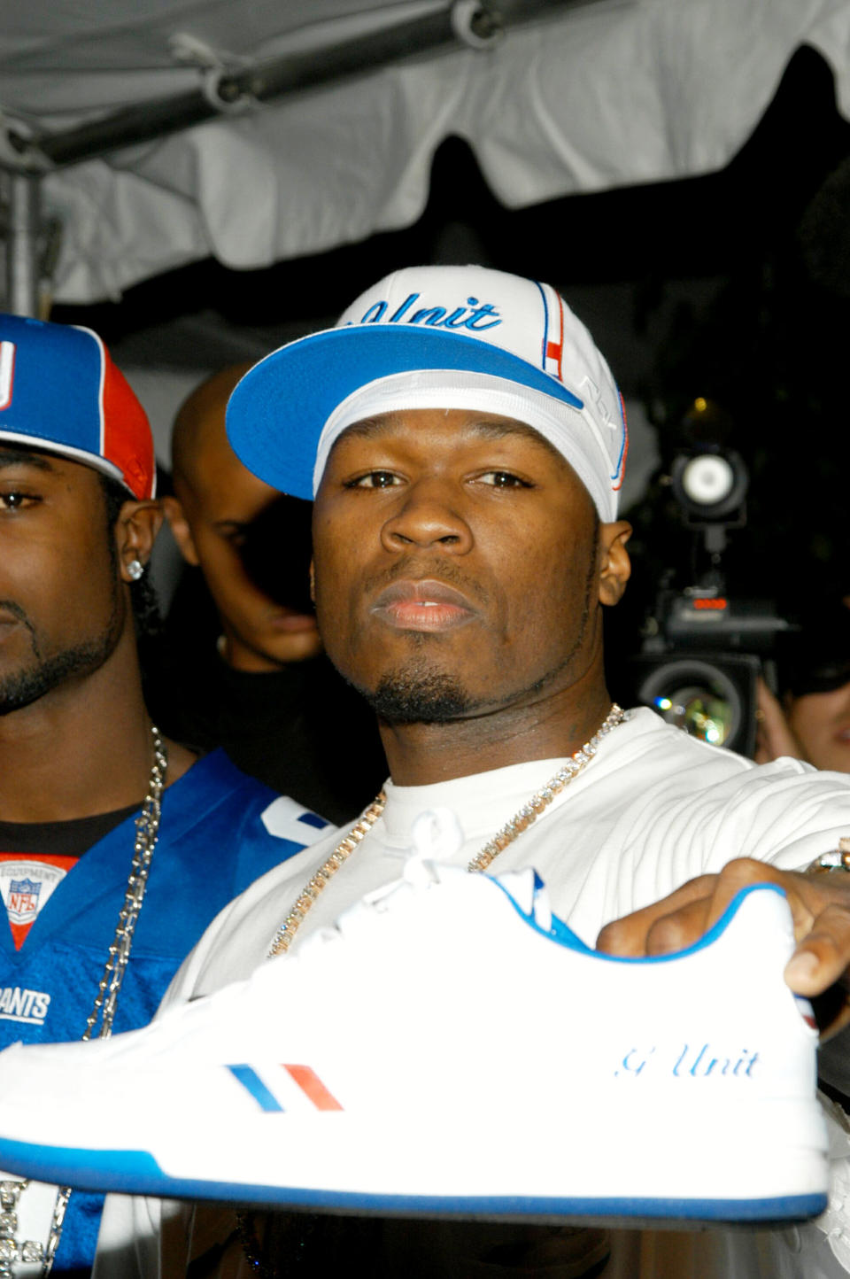 50 Cent holding up a white G Unit sneaker