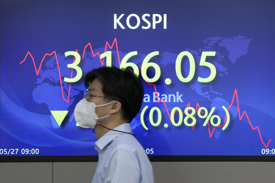 A currency trader walks by the screen showing the Korea Composite Stock Price Index (KOSPI) at the foreign exchange dealing room in Seoul, South Korea, Thursday, May 27, 2021. Asian shares fell Thursday, as investors watched for signs of inflation and awaited U.S. economic data expected later in the day. (AP Photo/Lee Jin-man)