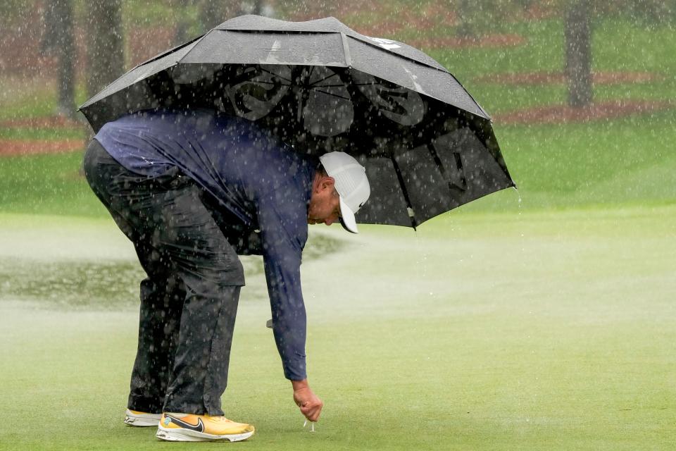 Brooks Koepka marks his ball for the evening on the seventh green after rain stopped play on Saturday afternoon at the Masters.