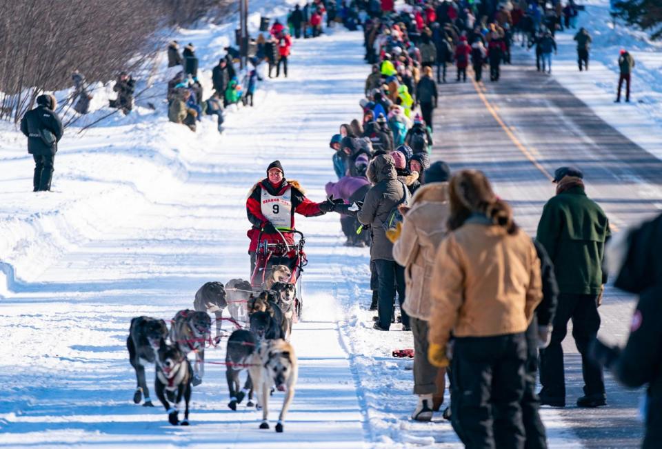 PHOTO: Laura Neese slaps the hands of attendees as her sled dog team takes off from the start line of the John Beargrease Sled Dog Marathon, Jan. 29, 2023, outside Billy's Bar in Duluth, Minn. (Alex Kormann/Star Tribune via Getty Images)