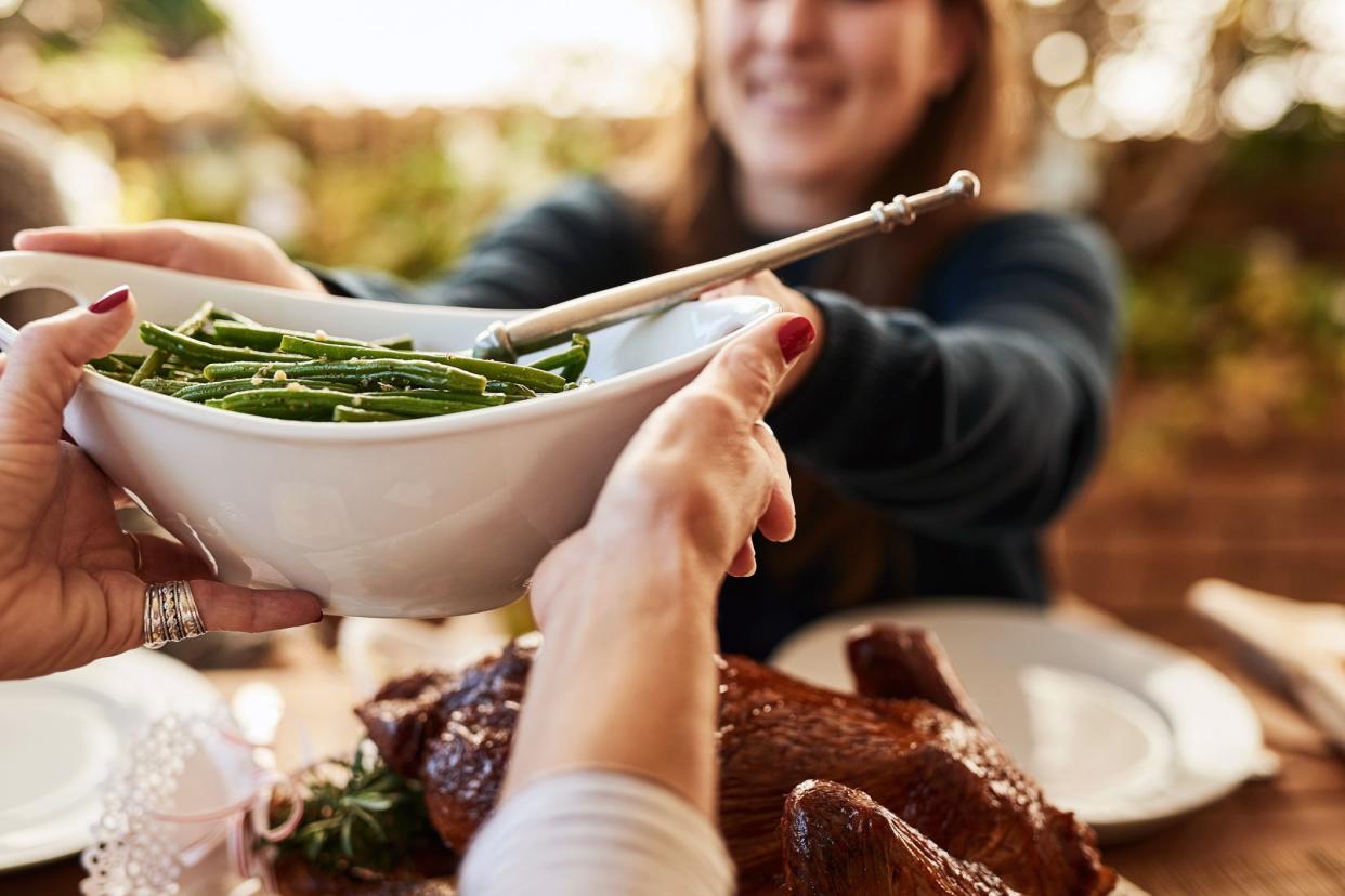 hands passing green beans to smiling young person