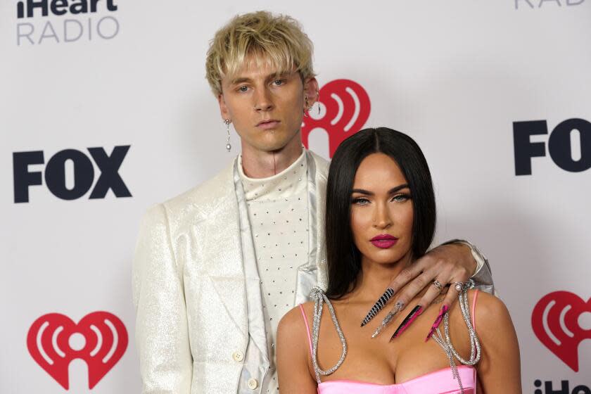 A man in a white suit posing with a woman in a pink dress