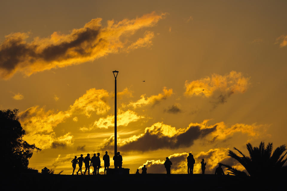 People gather at a headland as the sun rises at Coogee Beach in Sydney, Australia, Thursday, April 25, 2024. (AP Photo/Mark Baker)