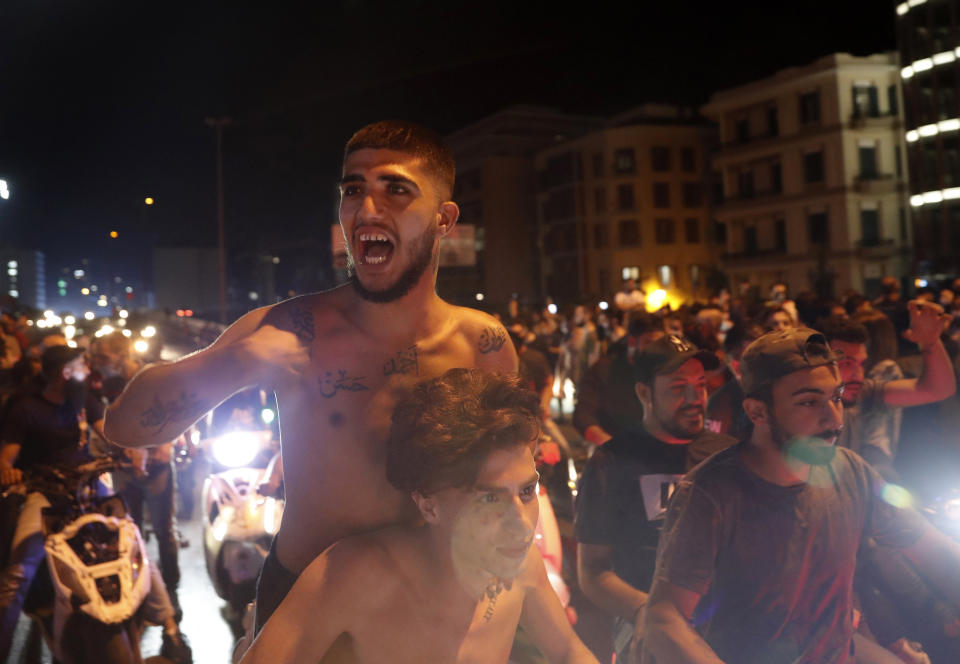 Anti-government protesters shout slogans, as they ride their scooters during a protest against the political leadership they blame for the economic and financial crisis, in front of the government house, in downtown Beirut, Lebanon, Thursday, June 11, 2020. (AP Photo/Hussein Malla)