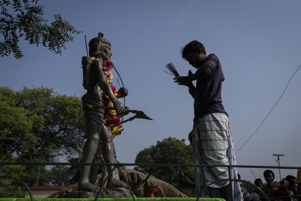 A tribesman prays in front of the statue of Birsa Munda, a 19th-century charismatic Indigenous leader who led his forest-bound community in revolt against British colonialists when they ruled India, in village Guduta, in the eastern Indian state of Odisha, Oct. 21, 2022. Munda's legend grew after his death and bronze statues of him appeared in almost every tribal village in the state. Soon, a man who worshipped nature was worshipped by his own people. Munda's religion barely survived the onslaught of conversions in his ancestral Ulihatu village. Half of his descendants have converted to Christianity. (AP Photo/Altaf Qadri)