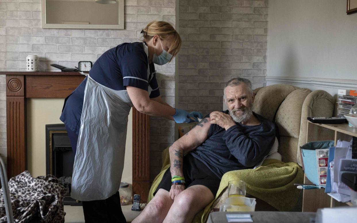 Team leader for housebound vaccinations, Julie Fletcher administers a dose of AstraZeneca/Oxford Covid-19 vaccine to housebound patient Graham Mullins at his home in Hasland, near Chesterfield, central England on April 14, 2021. -  AFP