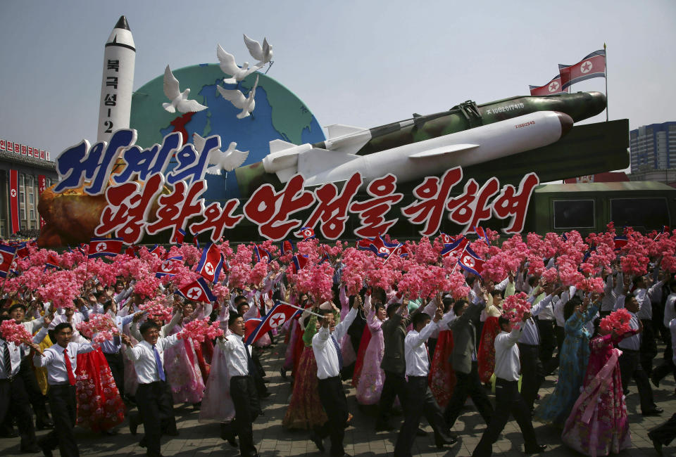 FILE - In this April 15, 2017, file photo, North Korean men and women wave flags and plastic flowers as a float with model missiles and rockets with words that read "For Peace and Stability in the World" is paraded across Kim Il Sung Square during a military parade in Pyongyang, North Korea. U.S. President Donald Trump and North Korean leader Kim Jong Un will likely be all smiles as they shake hands later this week in Hanoi for a meeting meant to put flesh on what many critics call their frustratingly vague first summit in Singapore. (AP Photo/Wong Maye-E, File)