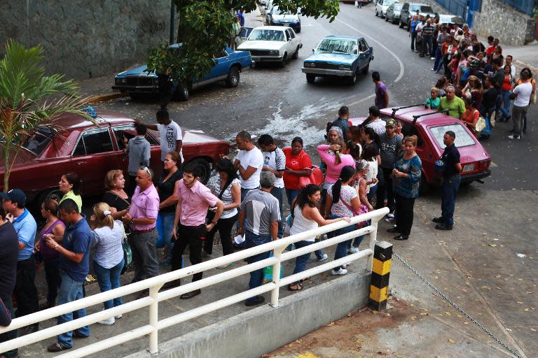 People queue up outside a supermarket to buy food in Caracas on April 2, 2014