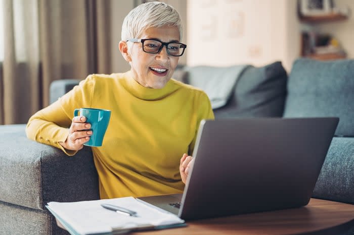 A person at a laptop holding a cup.