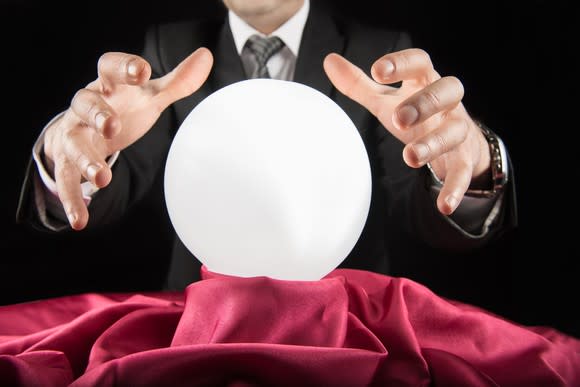 A man in a suit holds his hands above a crystal ball.