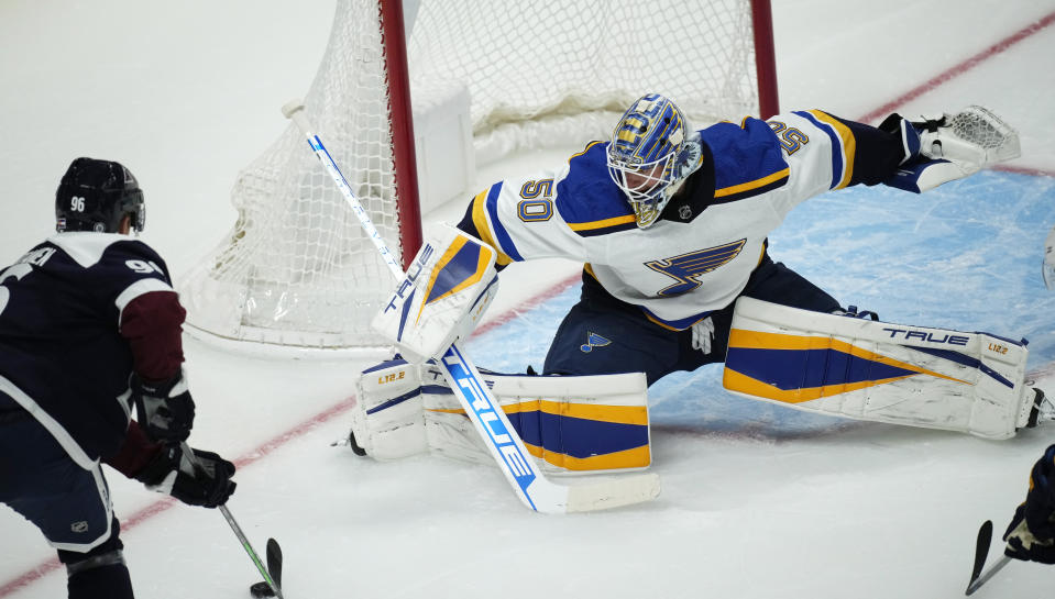 St. Louis Blues goaltender Jordan Binnington, right, protects the net as Colorado Avalanche center Nazem Kadri looks to shoot the puck in the first period of an NHL hockey game Saturday, Oct. 16, 2021, in Denver. (AP Photo/David Zalubowski)