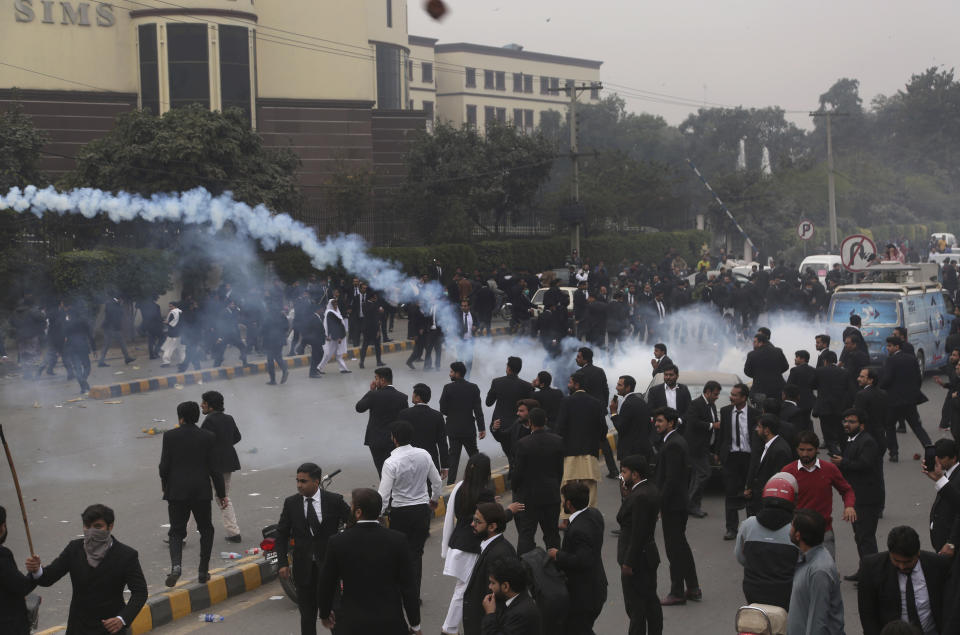 Police use tear gas shell to disperse angry lawyers back during a clash in Lahore, Pakistan, Wednesday, Dec. 11, 2019. Hundreds of Pakistani lawyers, angered over alleged misbehavior of some doctors toward one of their colleagues last month, stormed a cardiology hospital in the eastern city of Lahore, setting off scuffles with the facility's staff and guards that left heart patients unattended for several hours. (AP Photo/K.M. Chaudary)