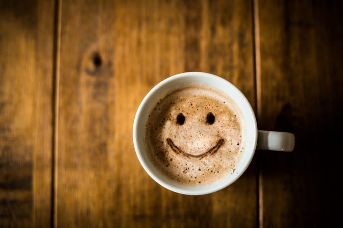 A smiley face made out of coffee and milk inside a coffee mug