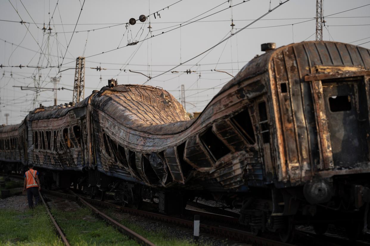 A railway worker stands next to heavily damaged train after a Russian attack on a train (Copyright 2022 The Associated Press. All rights reserved.)