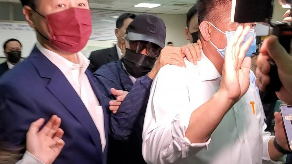 新光人壽前董事長吳東進戴著黑帽、太陽眼鏡及黑色口罩，躲在友人的身後進入新北地檢署。呂志明攝