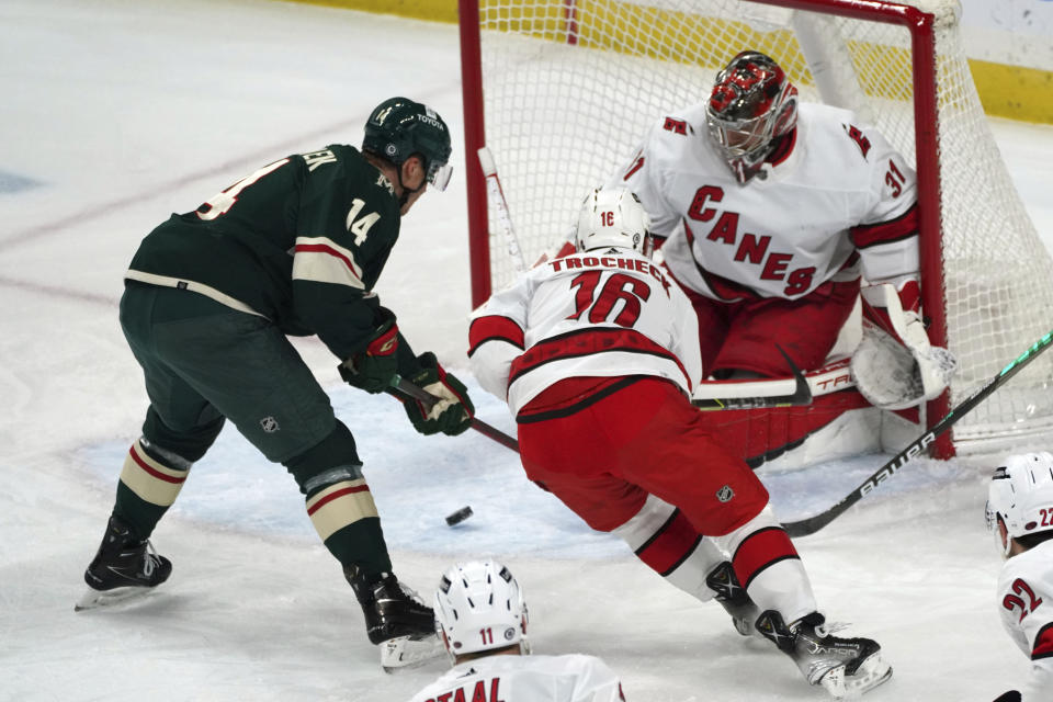 Minnesota Wild's Joel Eriksson Ek (14) looks at a rebound as Carolina Hurricanes' Derek Stepan (18) comes to the aid Hurricanes goalie Frederik Andersen (31) in the first period of an NHL hockey game, Saturday, Feb. 12, 2022, in St. Paul, Minn. (AP Photo/Jim Mone)