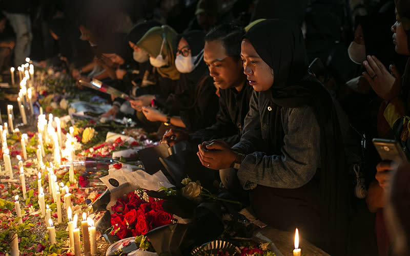 A woman weeps during a candlelight vigil for the victims of Saturday's soccer stampede