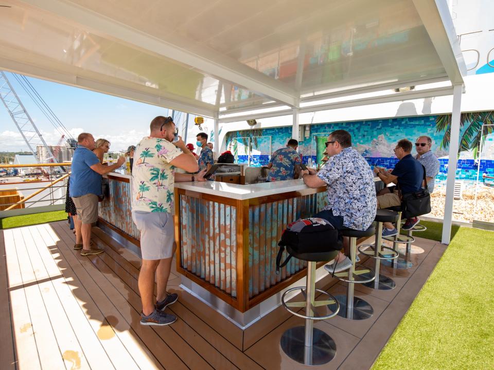 People sitting and standing around an outdoor bar.