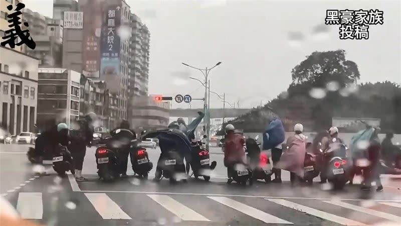 瞬間降下大雨，也讓待轉區內的騎士急忙穿上雨衣、雨褲。（圖／翻攝自黑色豪門企業）