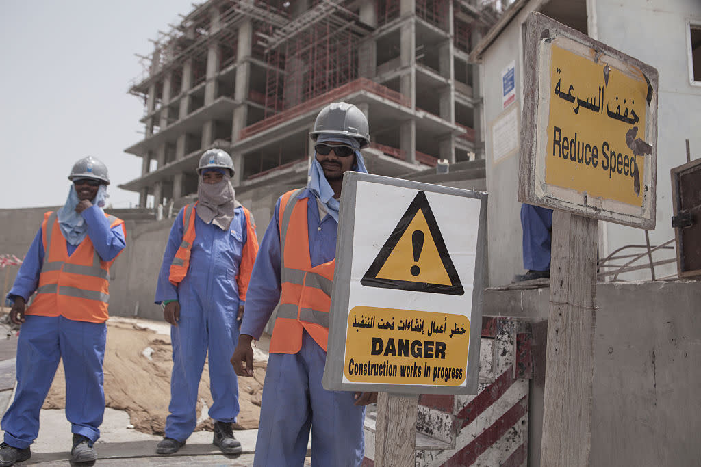 Migrant construction workers pose for a picture outside of their work site at The Pearl, a man-made chain of islands off the coast of northern Doha, which hosts dozens of high-rise luxury apartment complexes, villas, restaurants, and shops.