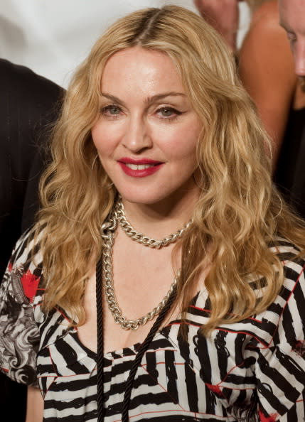 US musician Madonna wearing a black and white striped top, gold chain and with long wavy blonde hair loose.