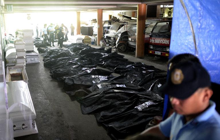 Body bags containing the remains of victims of a fire that gutted a footwear factory are lined up next to coffins at a makeshift morgue in Valenzuela City, suburban Manila, on May 14, 2015