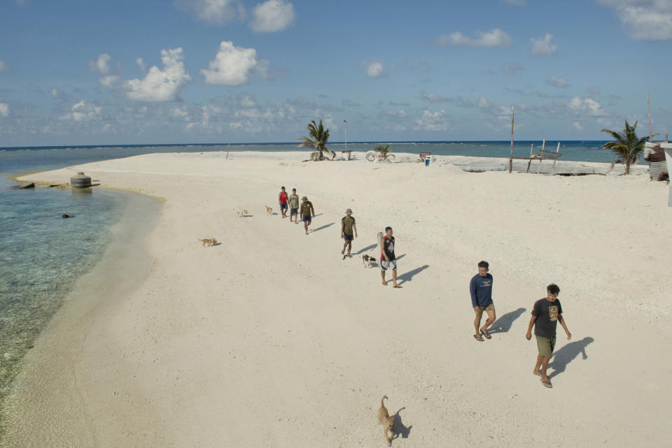 Seven Filipino soldiers walk with their dogs along the shoreline of Flat Island, May 8, 2016.