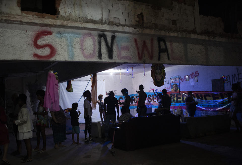 Members of the LGBTQ community gather in the courtyard of the squat known as Casa Nem to watch the weekly presentations by residents on a makeshift stage, in Rio de Janeiro, Brazil, Saturday, May 23, 2020. "Stonewall" is spray painted on an upper beam as a tribute to the Stonewall riots of 1969 in New York, the start of a rebellion that helped propel and transform the modern LGBTQ rights movement. (AP Photo/Silvia Izquierdo)
