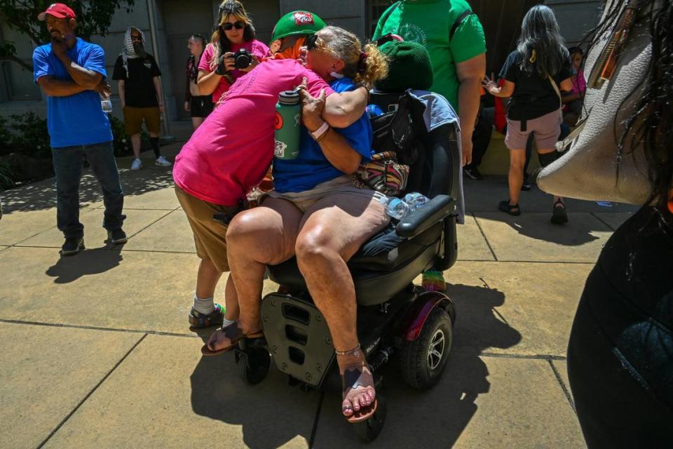 La cofundadora de Camp Resolution, Sharon Jones, abraza a Betty Edwards, habitante del campamento y recientemente operada del corazón, en una rueda de prensa en el Ayuntamiento de Sacramento, el miércoles 15 de mayo de 2024. Varias docenas de campistas, entre ellos Edwards, marcharon desde los juzgados de Sacramento hasta el Ayuntamiento en protesta por el cierre del campamento autónomo de personas sin hogar.