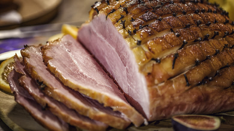 Sliced glazed ham on wooden board 