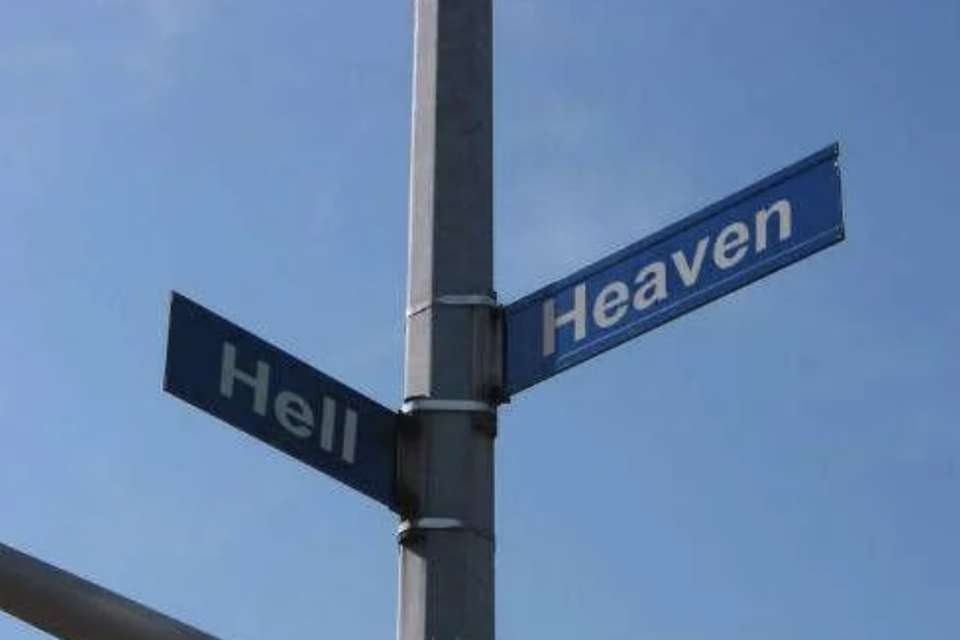 Street signs at an intersection labeled "Heaven" and "Hell" against a clear sky