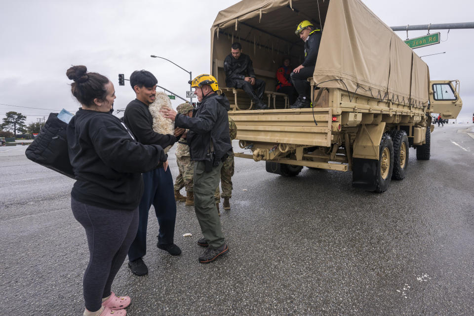 Two people and their dog are rescued from floodwaters in Watsonville, Calif., Saturday, March 11, 2023. (AP Photo/Nic Coury)