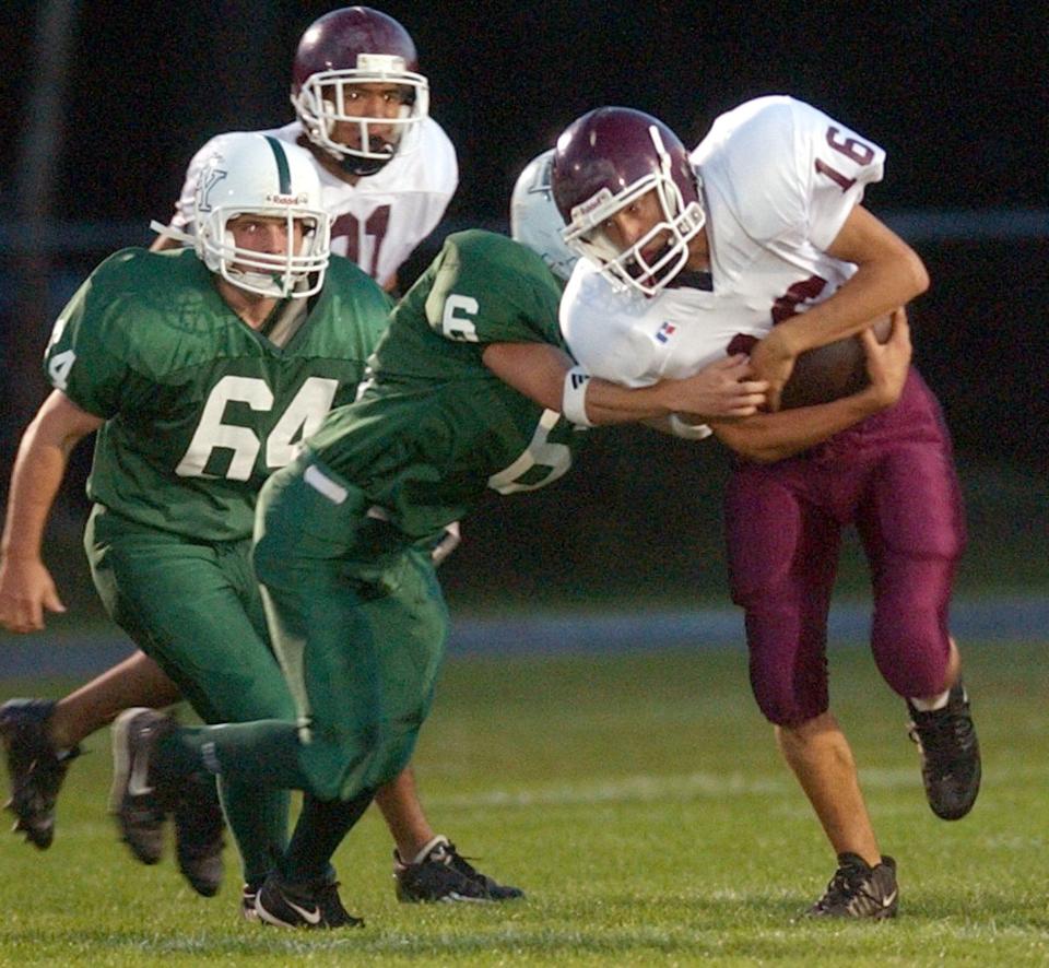 Lee Huffman Falmouth runs into the defensive pressure of Mark Lucier (6) and Chris Marsh (64) in the early going of a 2003 game.