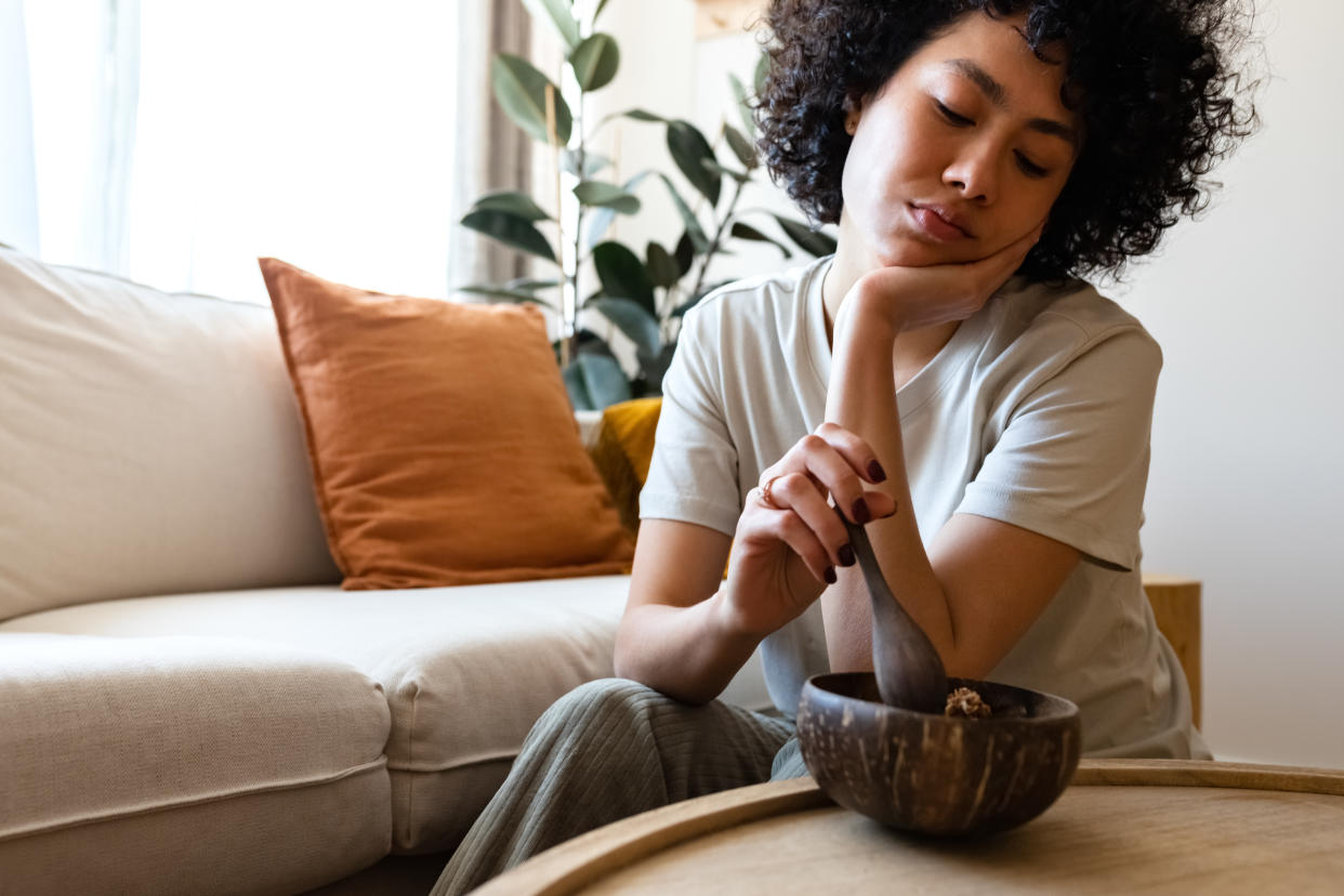 Young multiracial woman eating breakfast feeling very bored and unmotivated. Lack of appetite. Copy space. Lifestyle concept.