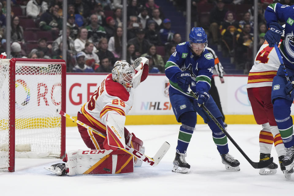 Calgary Flames goalie Jacob Markstrom (25) makes a save as Vancouver Canucks' Elias Pettersson (40) tries to get his stick on the puck during the third period of an NHL hockey game Friday, March 31, 2023, in Vancouver, British Columbia. (Darryl Dyck/The Canadian Press via AP)