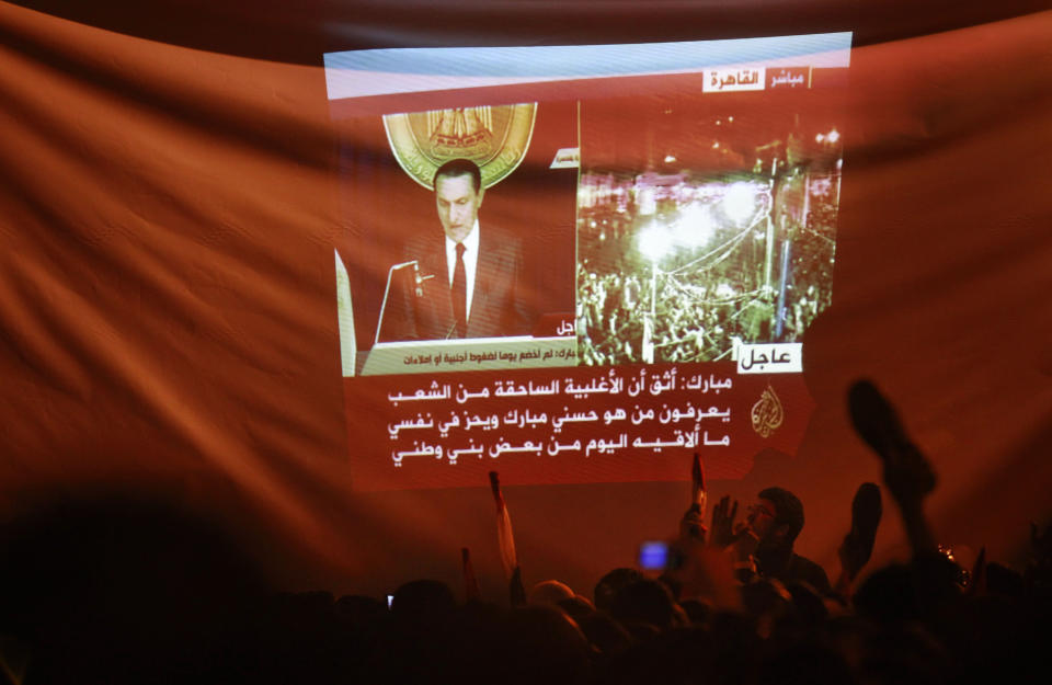 FILE - In this Feb. 10, 2011 file photo, protesters wave their shoes in the air in contempt as they watch a projection of the televised speech of Egyptian President Hosni Mubarak, in Cairo, Egypt. The 2011 uprising led to the quick ouster of autocrat Mubarak. A decade later, thousands are estimated to have fled abroad to escape a state, headed by President Abdel Fattah el-Sissi, that is even more oppressive. (AP Photo/Ben Curtis, File)