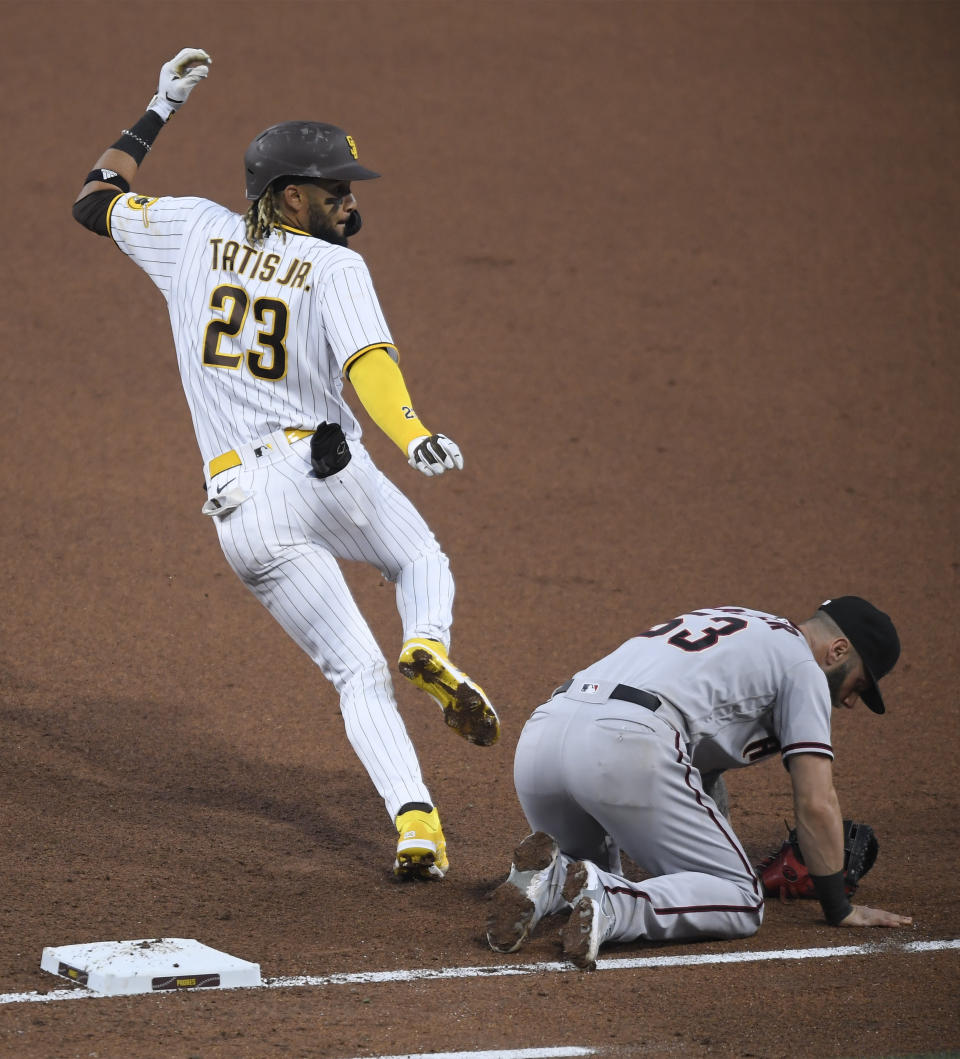 San Diego Padres' Fernando Tatis Jr. runs past Arizona Diamondbacks first baseman Christian Walker during the fourth inning of a baseball game Saturday, April 3, 2021, in San Diego. Walker was hit by the ball. Tatis advanced to second base. (AP Photo/Denis Poroy)