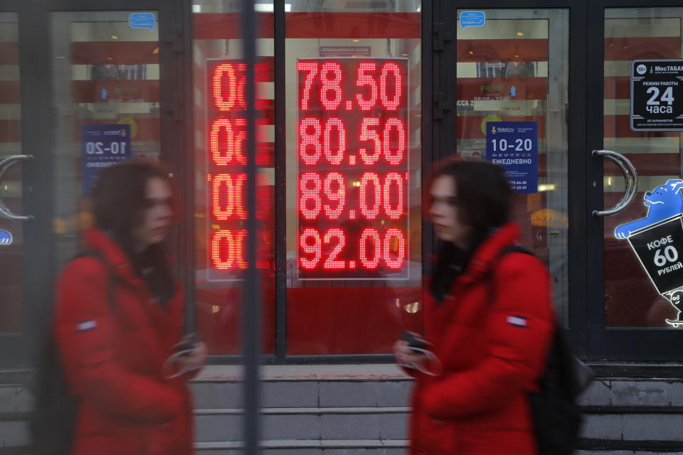 A woman walks at an exchange office screen showing the currency exchange rates of U.S. Dollar and Euro to Russian Rublesin Moscow, Tuesday, Feb. 22, 2022. The United States holds one of the most powerful financial weapons to wield against Putin if he invades Ukraine — blocking Russia from access to the U.S. dollar. Dollars still dominate in financial transactions around the world, with trillions of dollars in play daily. (AP Photo/Alexander Zemlianichenko Jr)