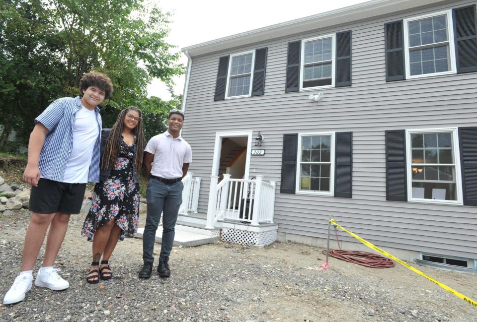 Jasmine Owens, center, is joined by her sons, Jordan Owens-Avala, left, and Andre Owens-Butler, right, outside their new home during the dedication of two new Habitat for Humanity homes in Hingham, Sunday, Aug. 27, 2023.