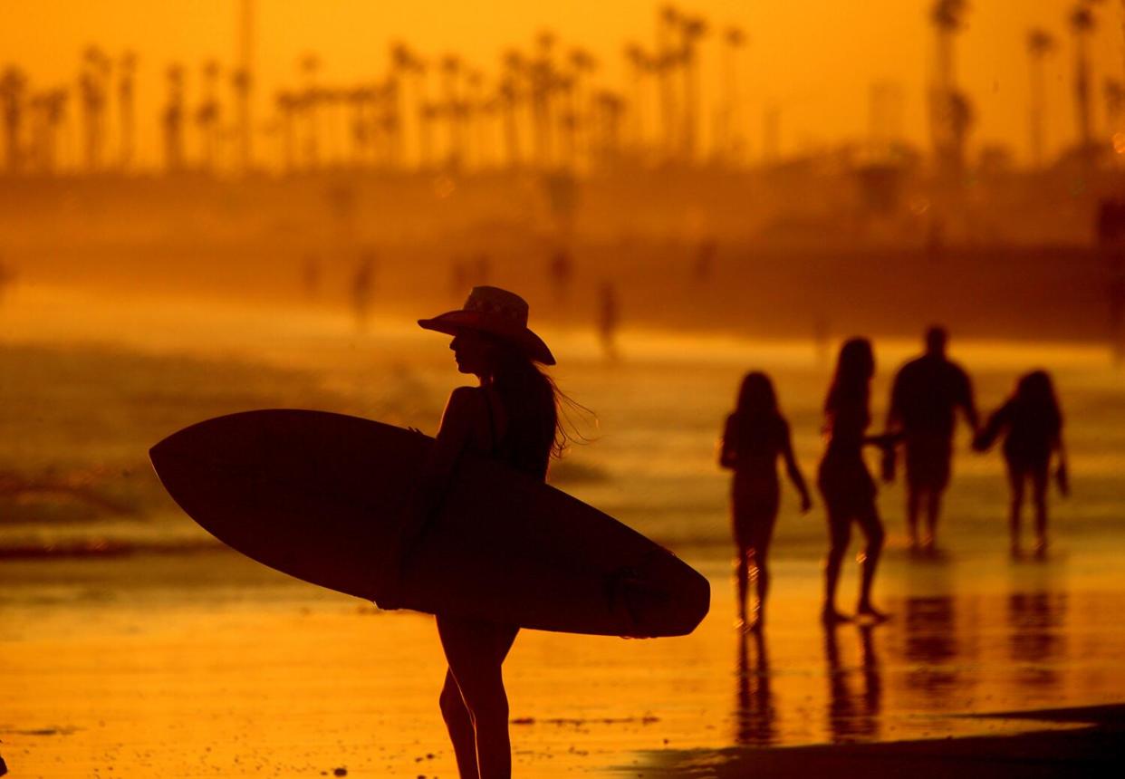 Beachgoers take in the cooling mist of the ocean as the sun sets on Huntington Beach.