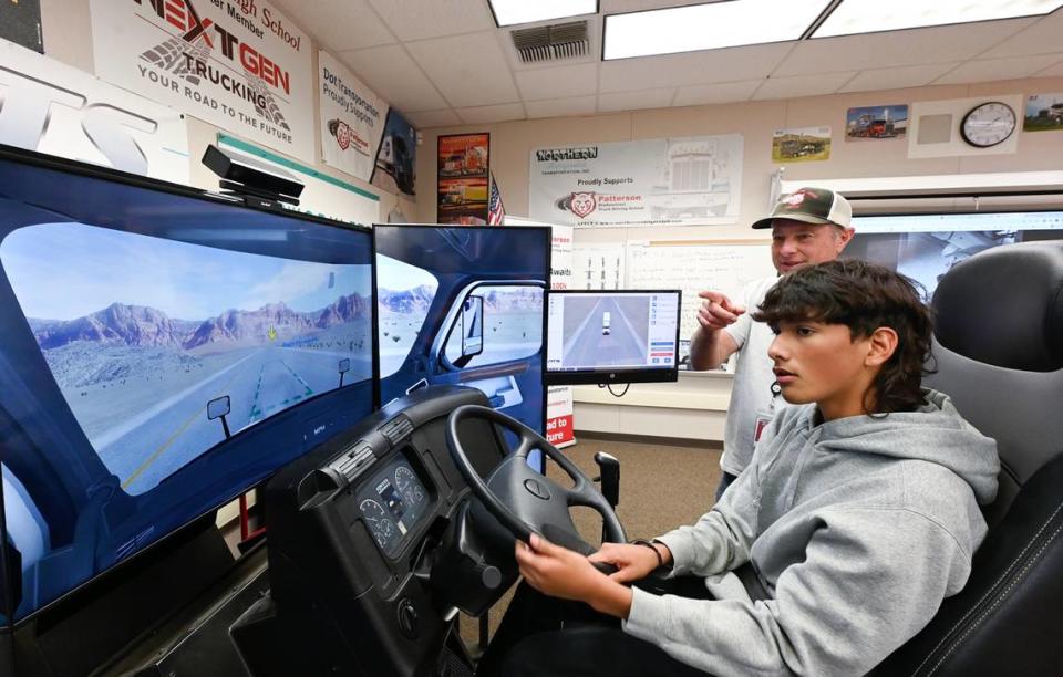 Miguel Lopez works on backing skills on a trucking simulator with the help of teacher David Dein at Patterson High School in Patterson, Calif., Friday, Oct. 27, 2023. The school has career technical education class to teach trucking and help students gain a commercial drivers permit.